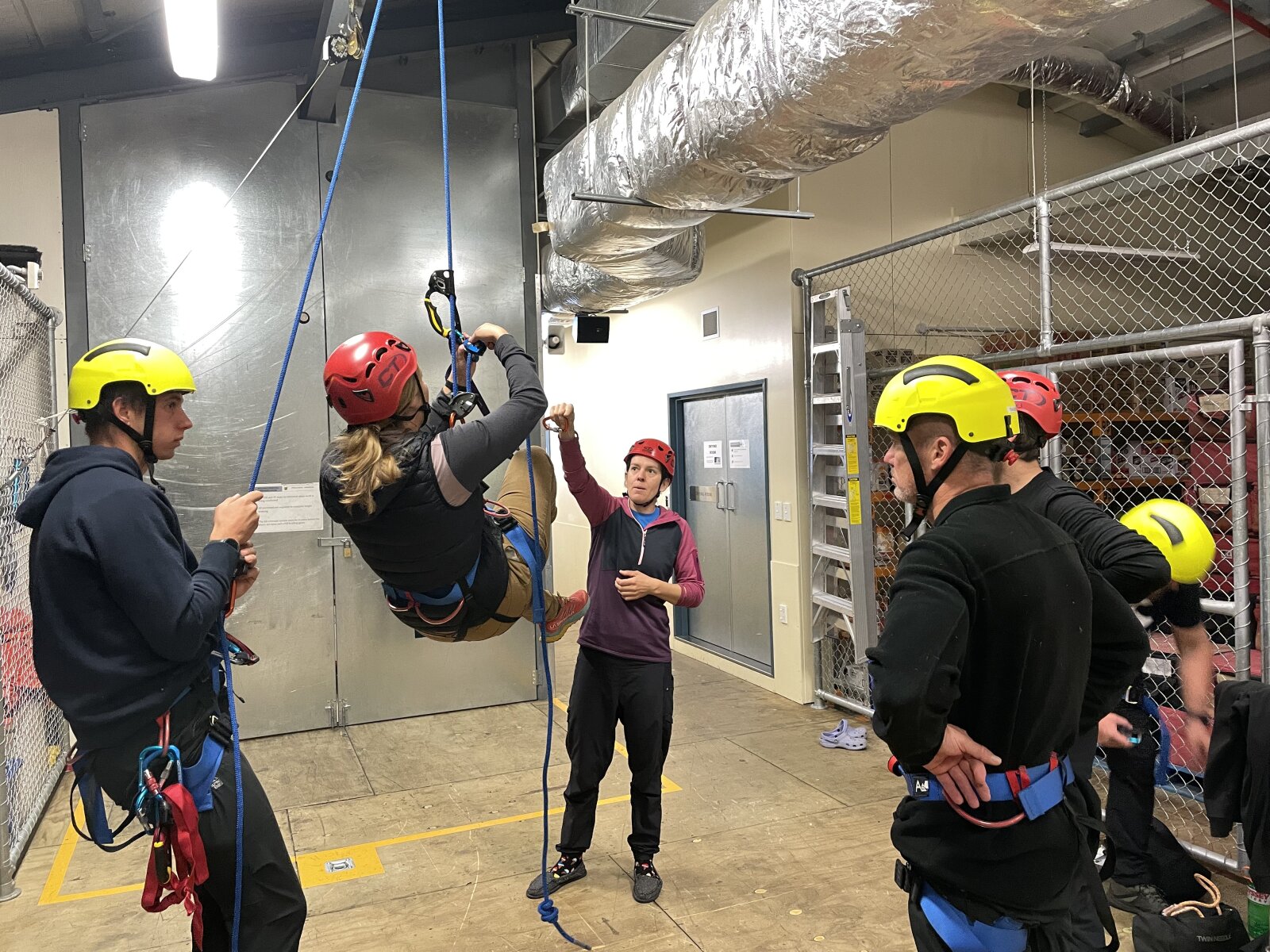 People in the Hillary Field Centre, climbing ropes looped over a rafter